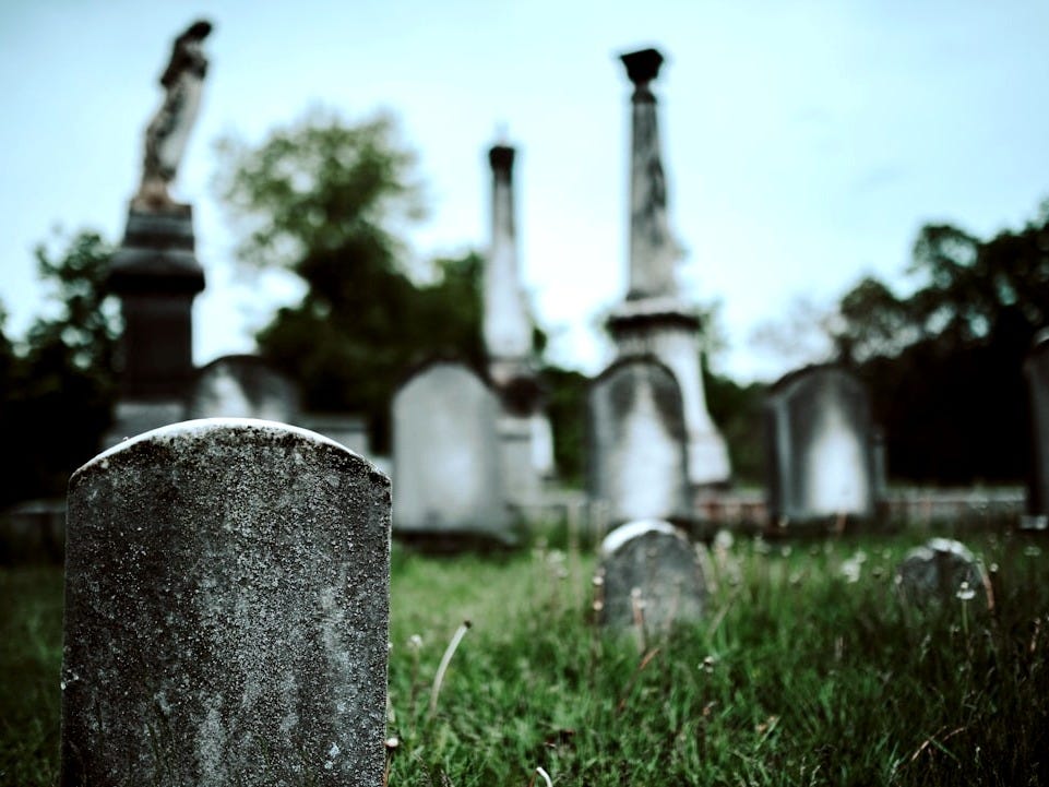 gray concrete cross on green grass field during daytime