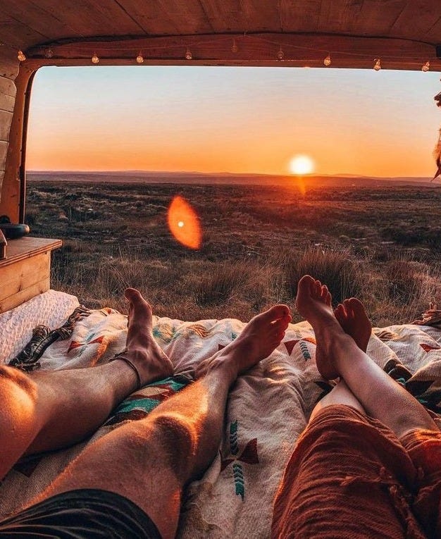 This may contain: two people laying in the back of a truck at sunset