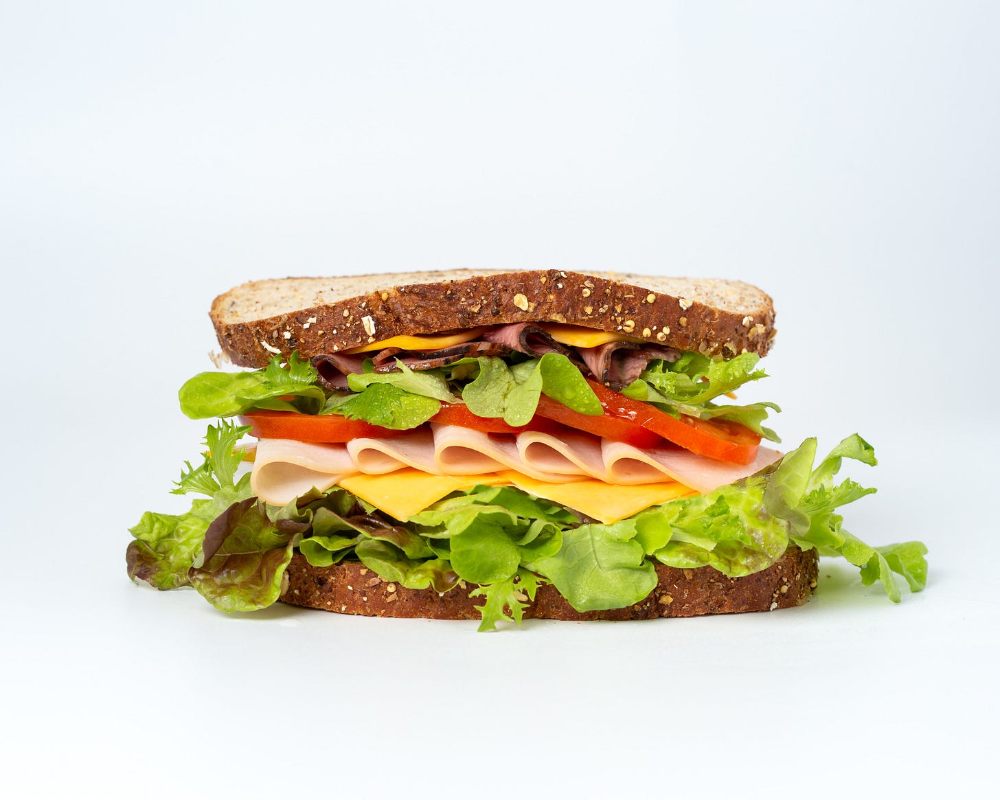 a sandwich with lettuce tomato and cheese on a white background