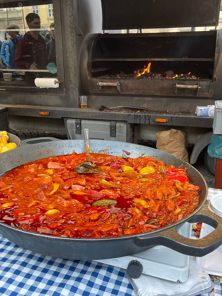 Classic Czech carnival fare — smoky sausages, golden potatoes, and roasted red peppers — the kind of hearty, unfussy food eaten standing up during Masopust celebrations.