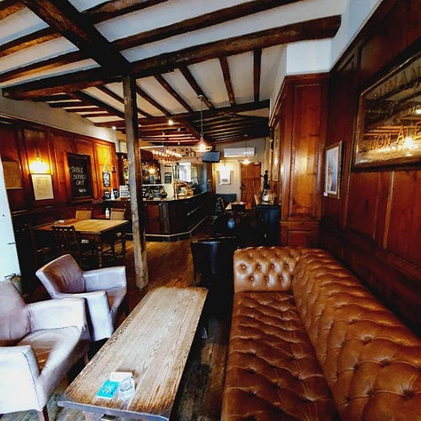 The KIngs Head hotel with people smiling outside and working on a laptop inside the bar