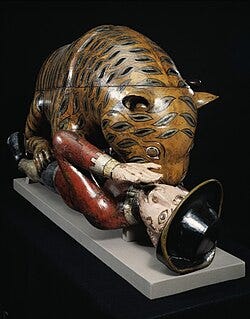 The eighteenth-century automaton in the V&A: a carved and painted wooden tiger, striped in black on ochre, crouched over a supine European soldier in a red coat, on a pale plinth against a black ground.
