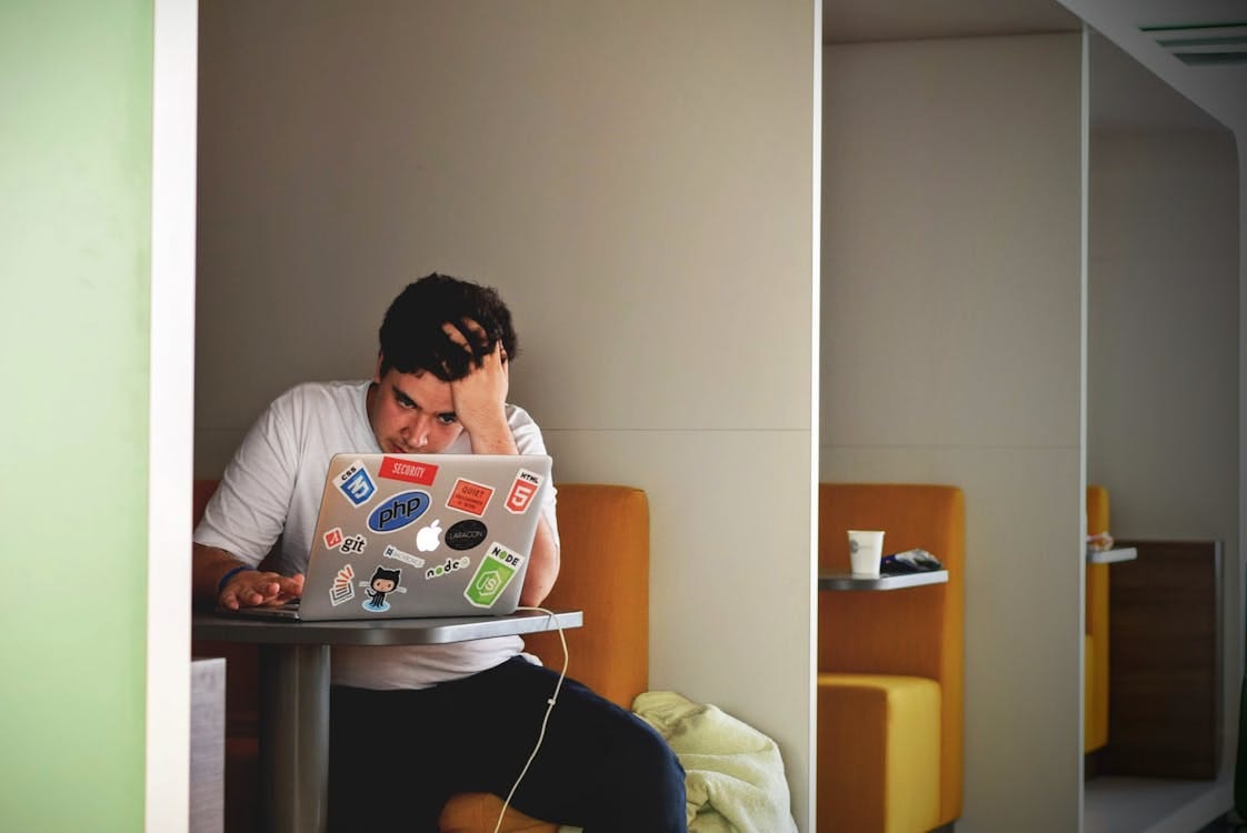 Free Man showing stress and frustration while working remotely on a laptop indoors. Stock Photo Free Man showing stress and frustration while working remotely on a laptop indoors. Stock Photo