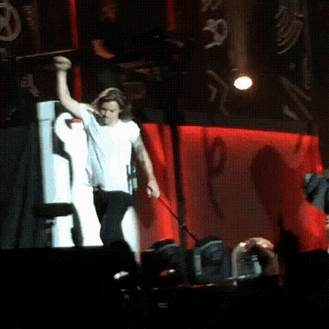Harry Styles on stage, walking triumpantly, but then his mic catches on the stage and pulls him backwards before he falls down.
