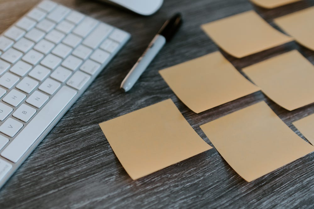 Lots of blank sticky notes on a desk next to a marker and keyboard