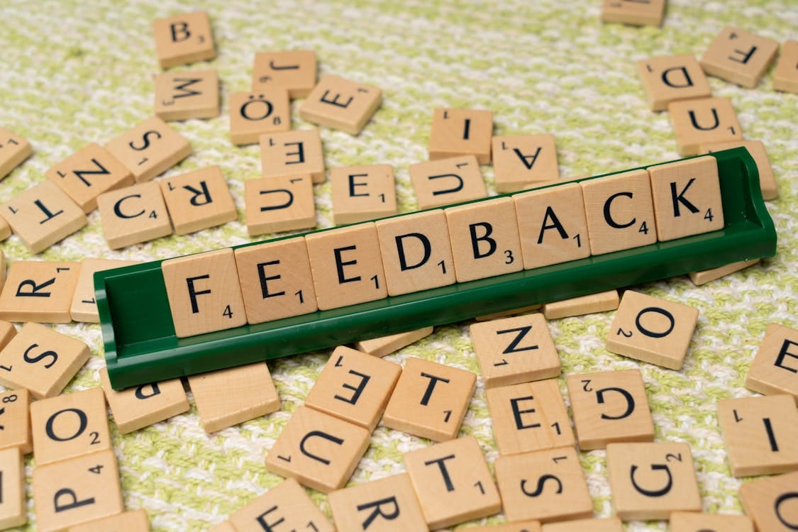 Free Wooden letter tiles spelling 'feedback' on a green rack, representing communication and evaluation. Stock Photo Free Wooden letter tiles spelling 'feedback' on a green rack, representing communication and evaluation. Stock Photo