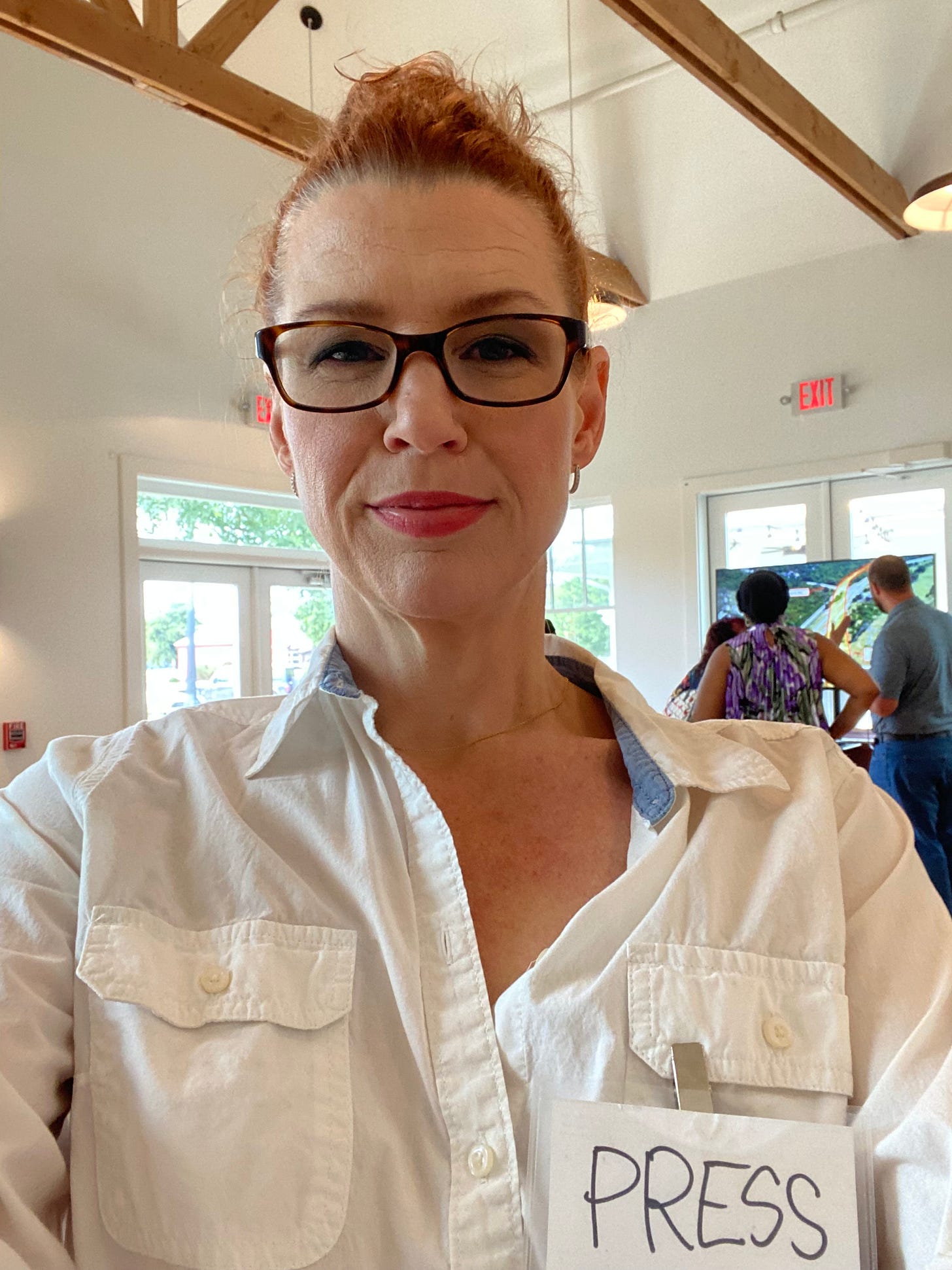 A beautiful woman wearing glasses and a makeshift press pass