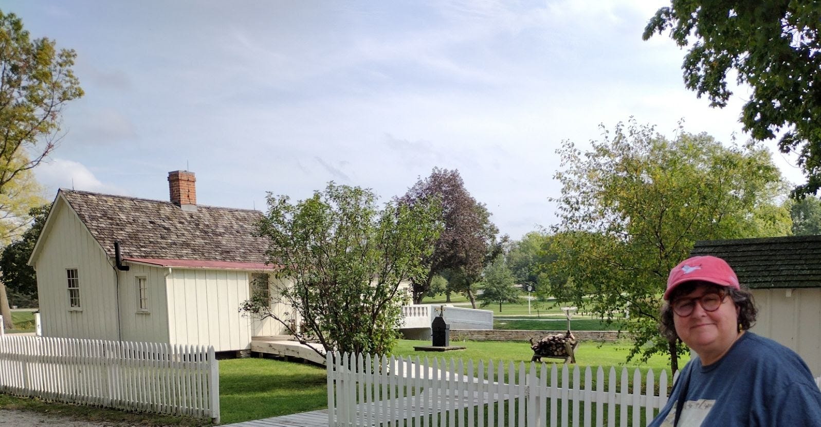 Tiny cottage with lean-to in back, and Annette in tourist mode, including peaked cap