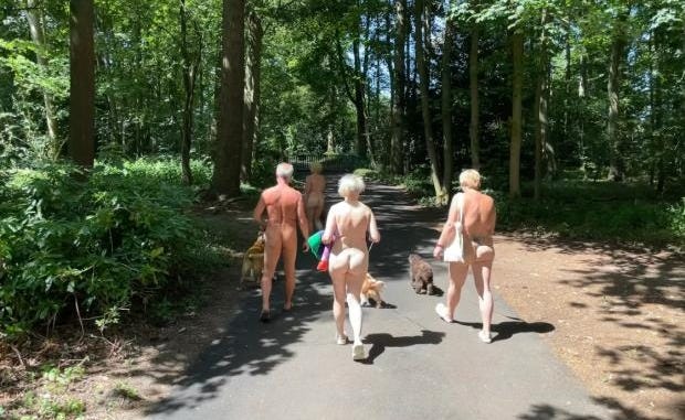 Three nude people walk on a shady paved path at Broadland Sun Club