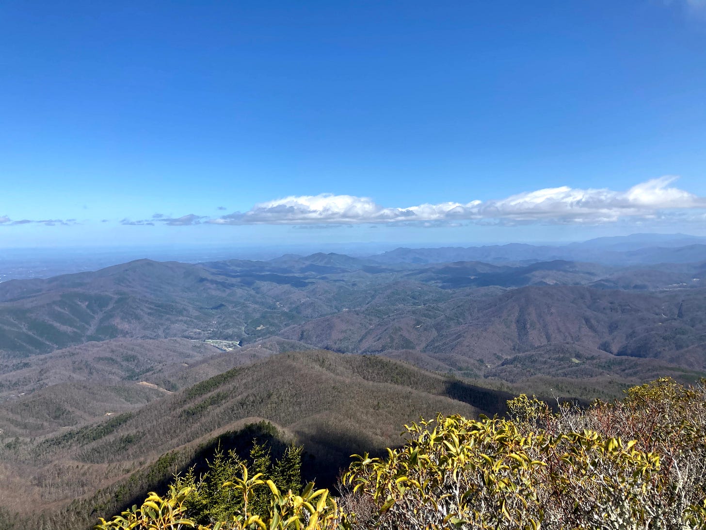 view of mountains under a blue sky with a few fluffy clouds in the horizon