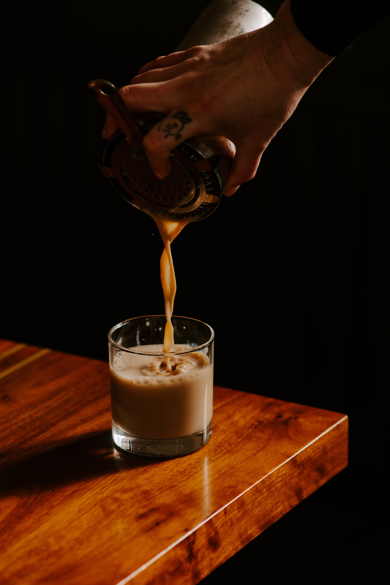 Drink being poured from a shaker into a cocktail glass