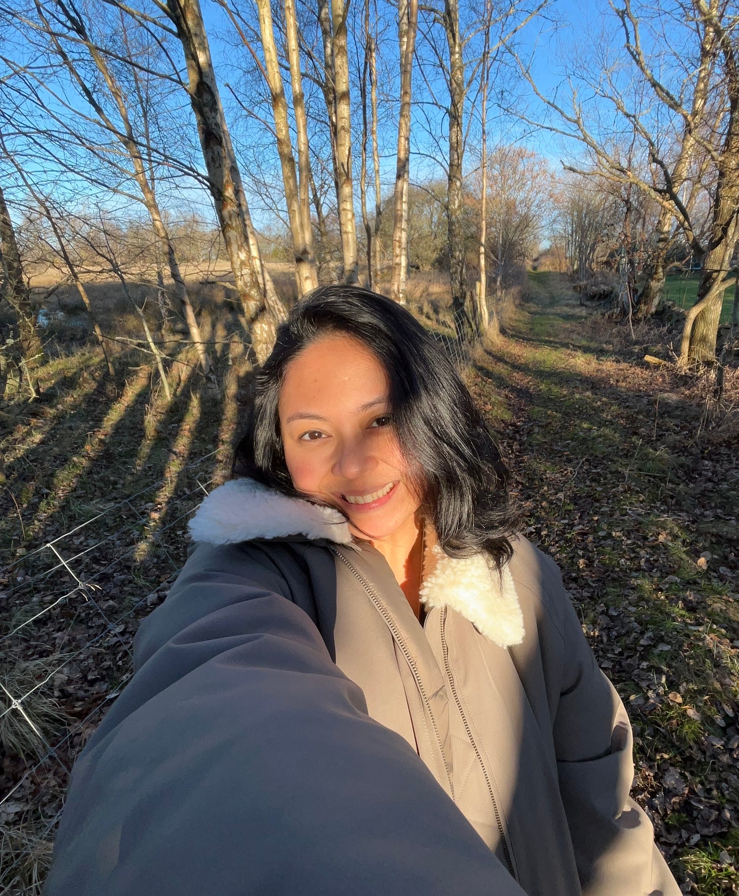 A portrait of the author smiling and at peace in a sunlit forest, representing the journey toward internal alignment and healing out loud