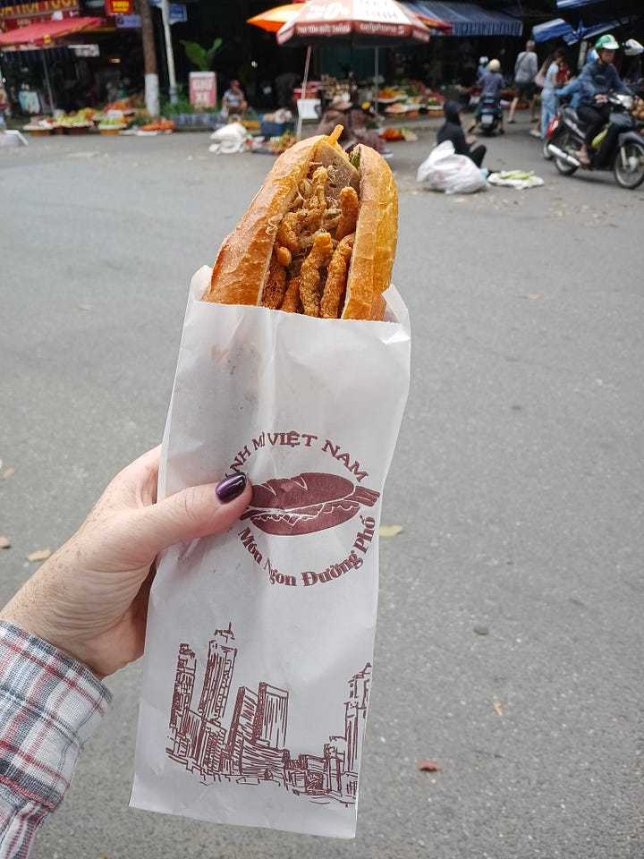 Vietnamese vegetarian sandwich being held in a hand, food cart