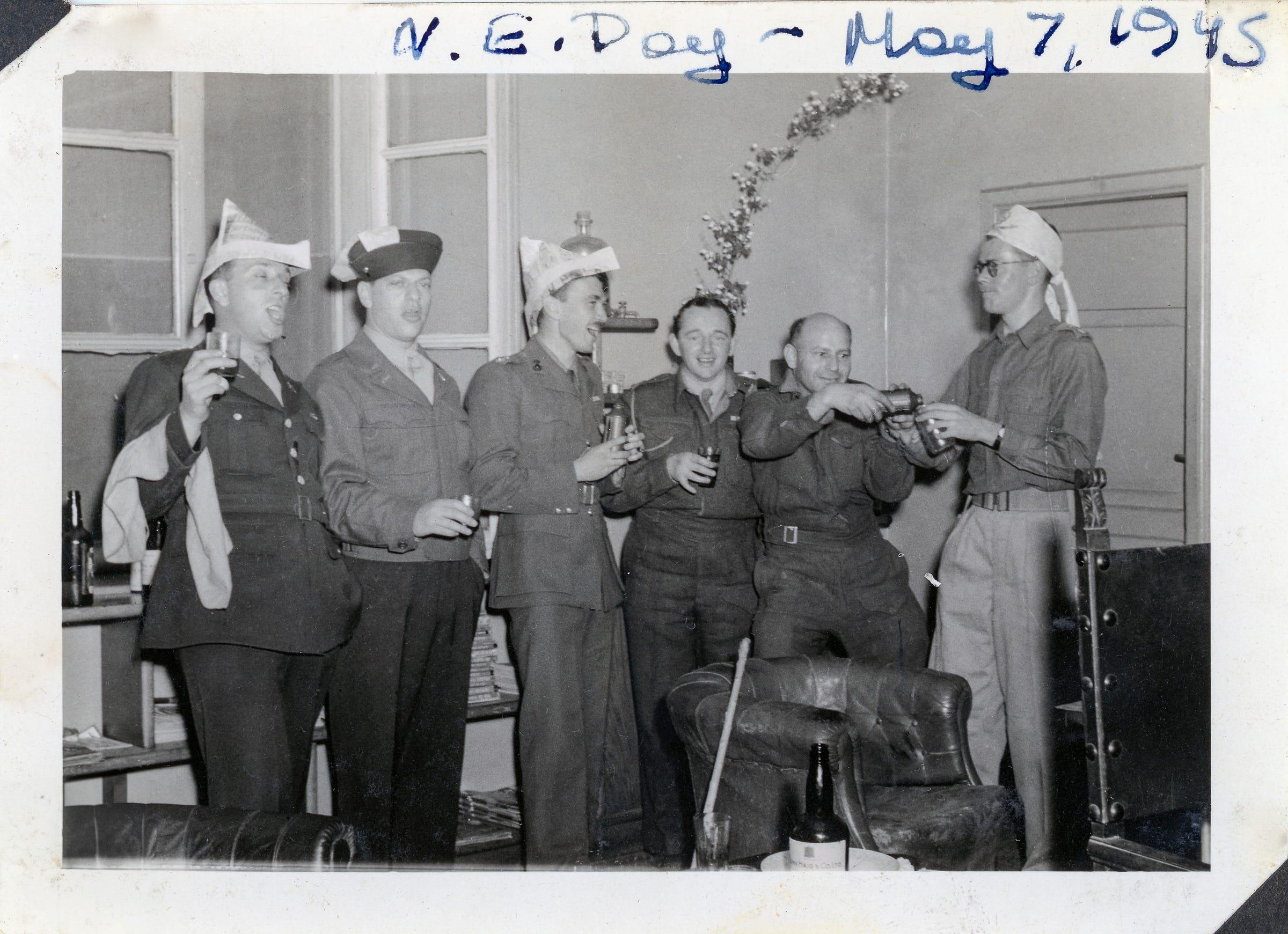 Dressed in full military uniform, wearing a triangular-shaped party hat made from newspaper, and raising a glass of John Haig and Co Scotch Whiskey, my grandpa Norman “Norm” celebrated Victory in Europe (V-E) day in Rome with a few of his fellow Army comrades. Dressed in full military uniform, wearing a triangular-shaped party hat made from newspaper, and raising a glass of John Haig and Co Scotch Whiskey, my grandpa Norman “Norm” celebrated Victory in Europe (V-E) day in Rome with a few of his fellow Army comrades.