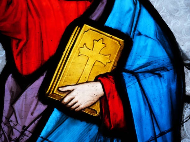 a hand holds the bible against the toga of a religious person.close-up of a colorful stained glass window backlit by the sun. natural colors.photograph taken in an abandoned funeral chapel at the pere lachaise cemetery in paris, france. - holy bible stock pictures, royalty-free photos & images