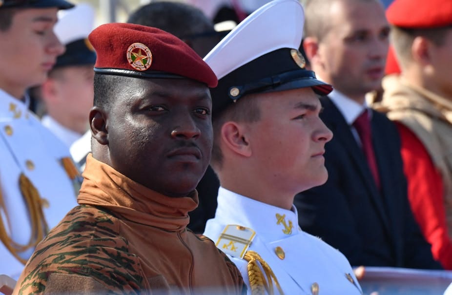 Man in red beret and military uniform, pictured amid other men in military uniforms