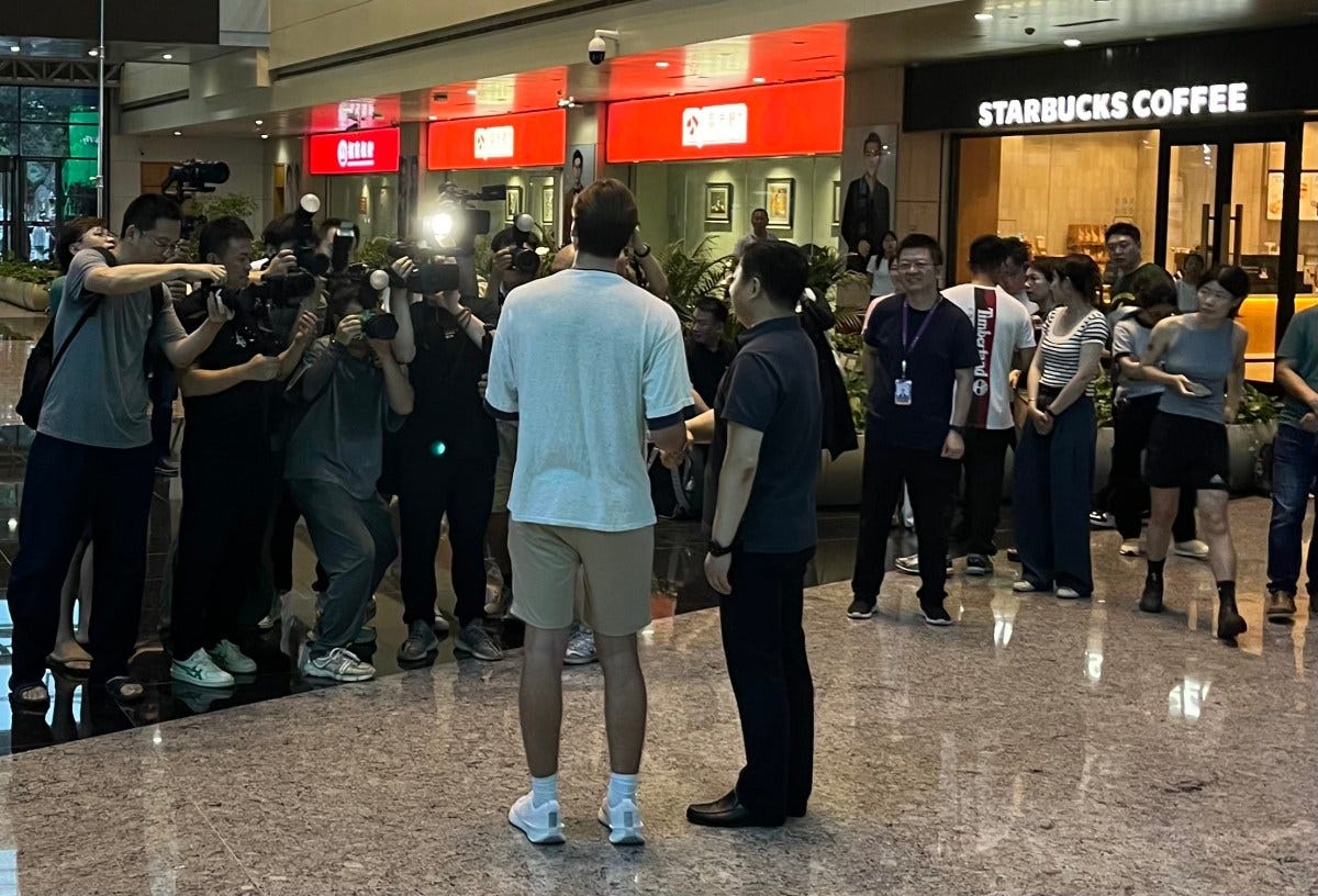 Two men stand in front of cameras