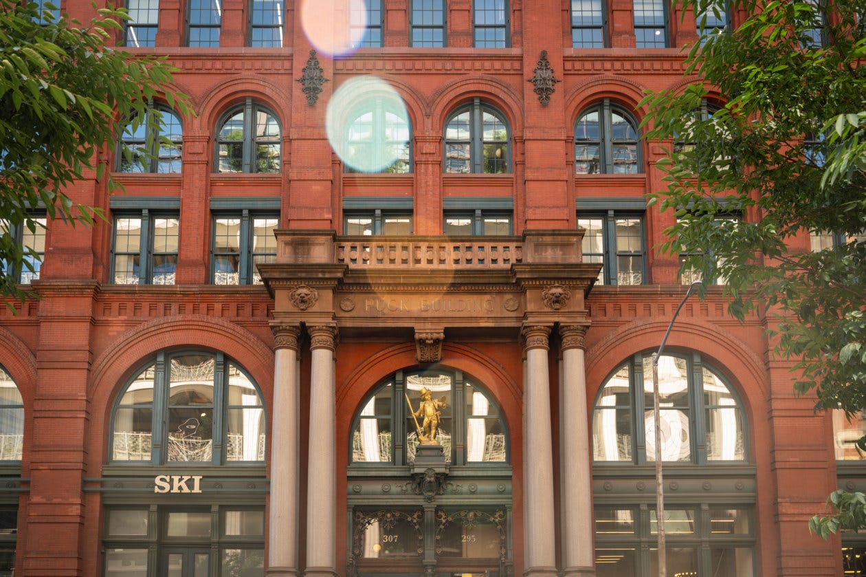 The Puck Building, a red brick building with arched windows and a golden statue of Puck, in New York City. The Puck Building, a red brick building with arched windows and a golden statue of Puck, in New York City.