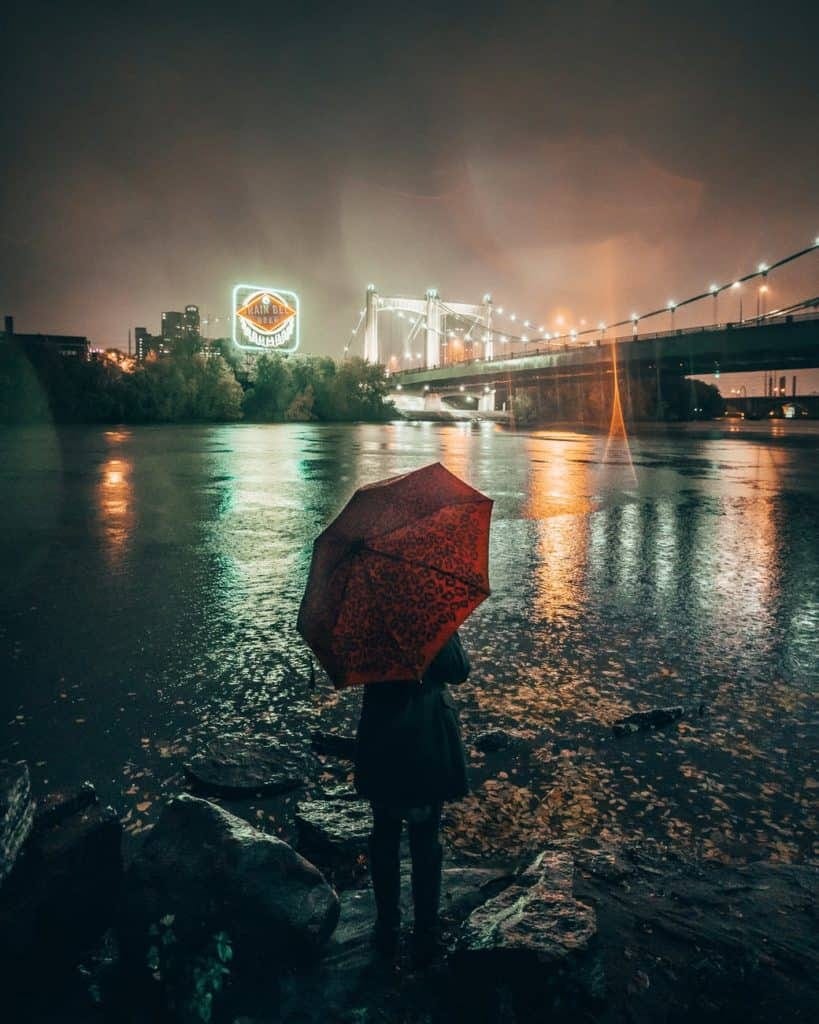 Woman with Red Umbrella Standing at Riverbank