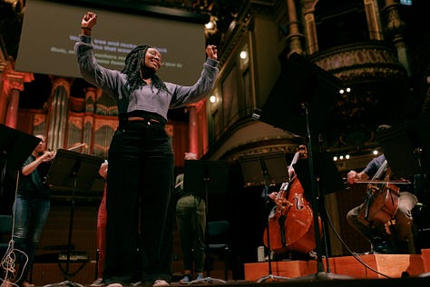 Actress Vilma Jackson, using sign language, standing in the middle of the stage, surrounded by United Strings of Europe musicians