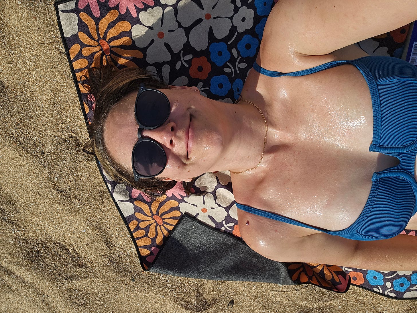 Cassidy laying on the beach in a blue bathing suit