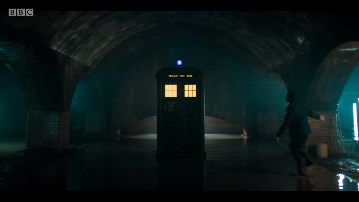 This image shows the TARDIS sitting in Sheffield, England's impressively arched sewers in "Resolution" (Doctor Who's 2019 New Year's Day Special). To its left (but to this image's right) is Nikesh Patel's character, Mitch, walking toward the materializing TARDIS.