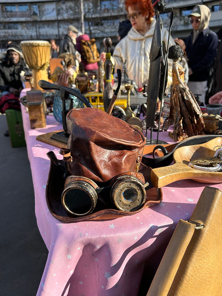 Flea market clothes, shoes, cameras, vintage tableware displayed on tables an an outdoor market