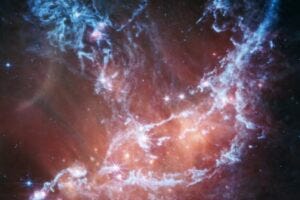 This new infrared image of NGC 346 from NASA’s James Webb Space Telescope’s Mid-Infrared Instrument (MIRI) traces emission from cool gas and dust. In this image blue represents silicates and sooty chemical molecules known as polycyclic aromatic hydrocarbons, or PAHs. More diffuse red emission shines from warm dust heated by the brightest and most massive stars in the heart of the region. Bright patches and filaments mark areas with abundant numbers of protostars. This image includes 7.7-micron light shown in blue, 10 microns in cyan, 11.3 microns in green, 15 microns in yellow, and 21 microns in red (770W, 1000W, 1130W, 1500W, and 2100W filters, respectively).