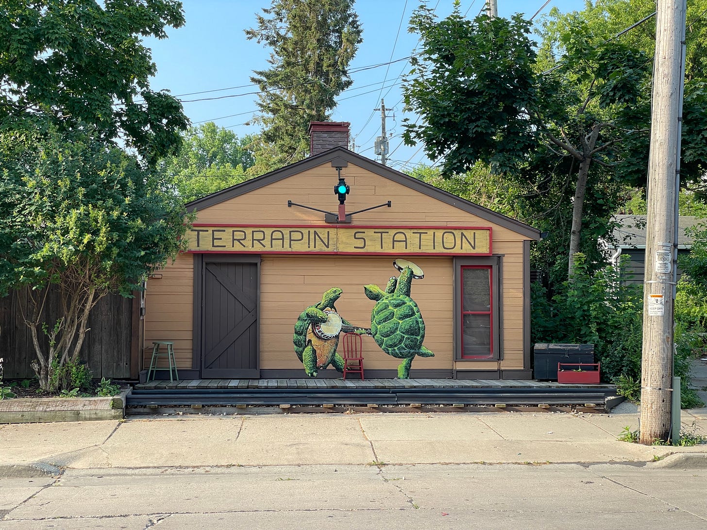 A photo of a Riverwest, Milwaukee garage that has been labeled "Terrapin Station" and decorated with a mural of turtles playing instruments, along with real train-yard decor.