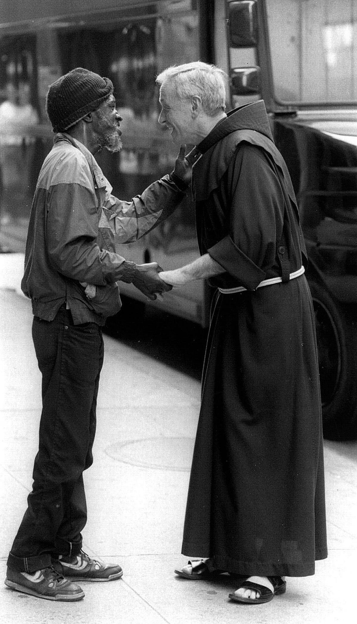 Father Mychal Judge greets a man on a Manhattan sidewalk