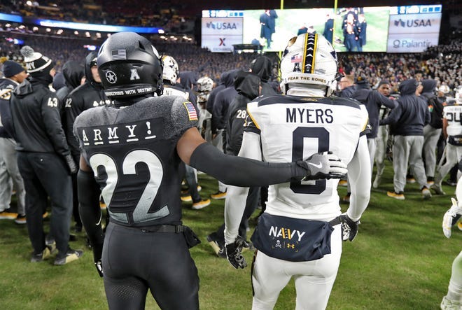 Army running back Miles Stewart (22) puts his arm around Navy wide receiver Kroy Myers (0) after the game.