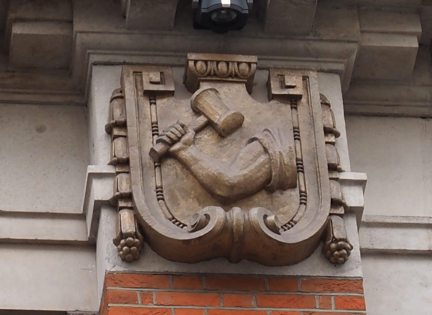 Arm and Hammer carving on building front.