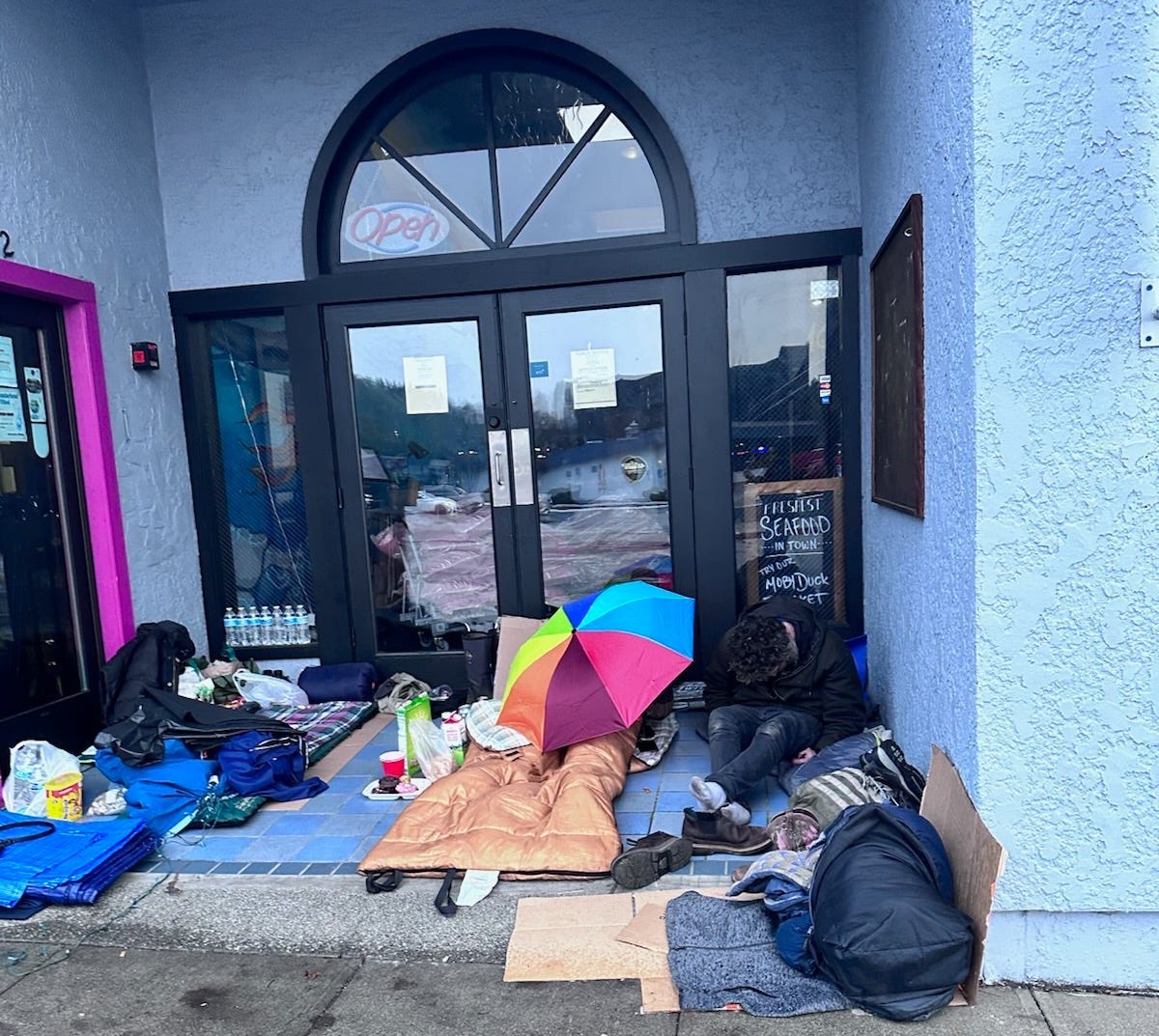 A person sitting on the ground outside of a building
Description automatically generated A person sitting on the ground outside of a building
Description automatically generated