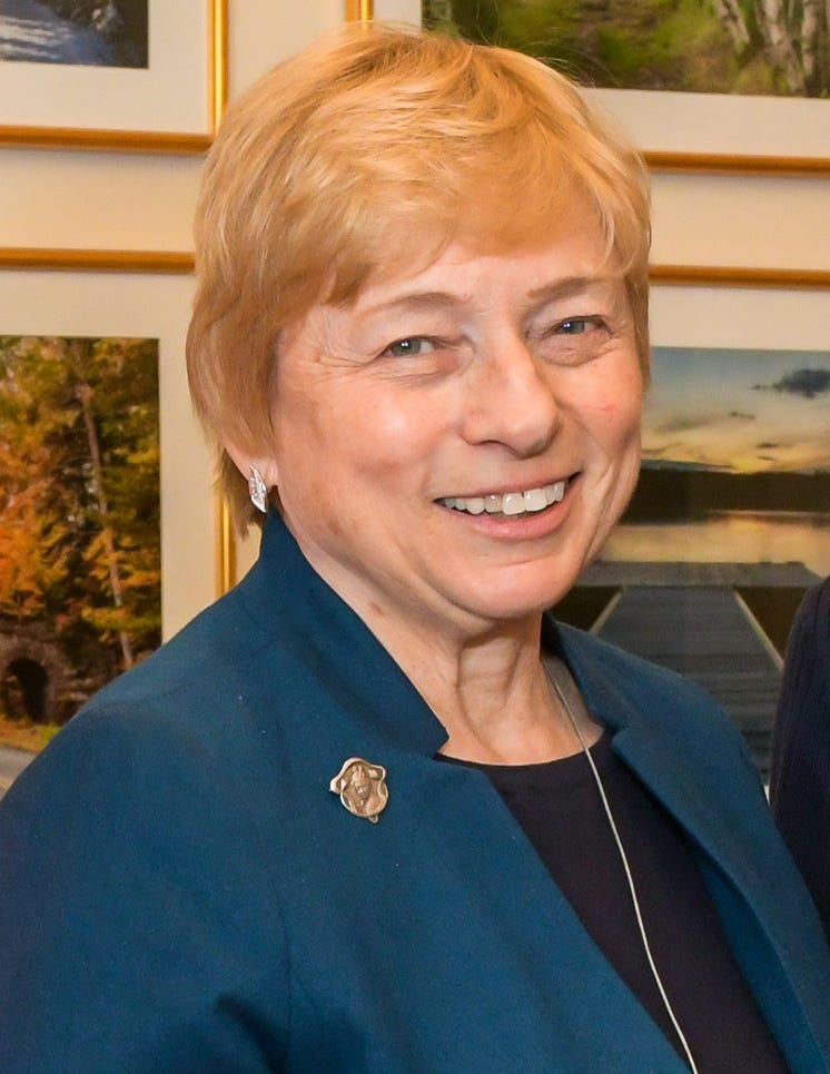 Janet Mills headshot; smiling with orange hair and a blue blouse