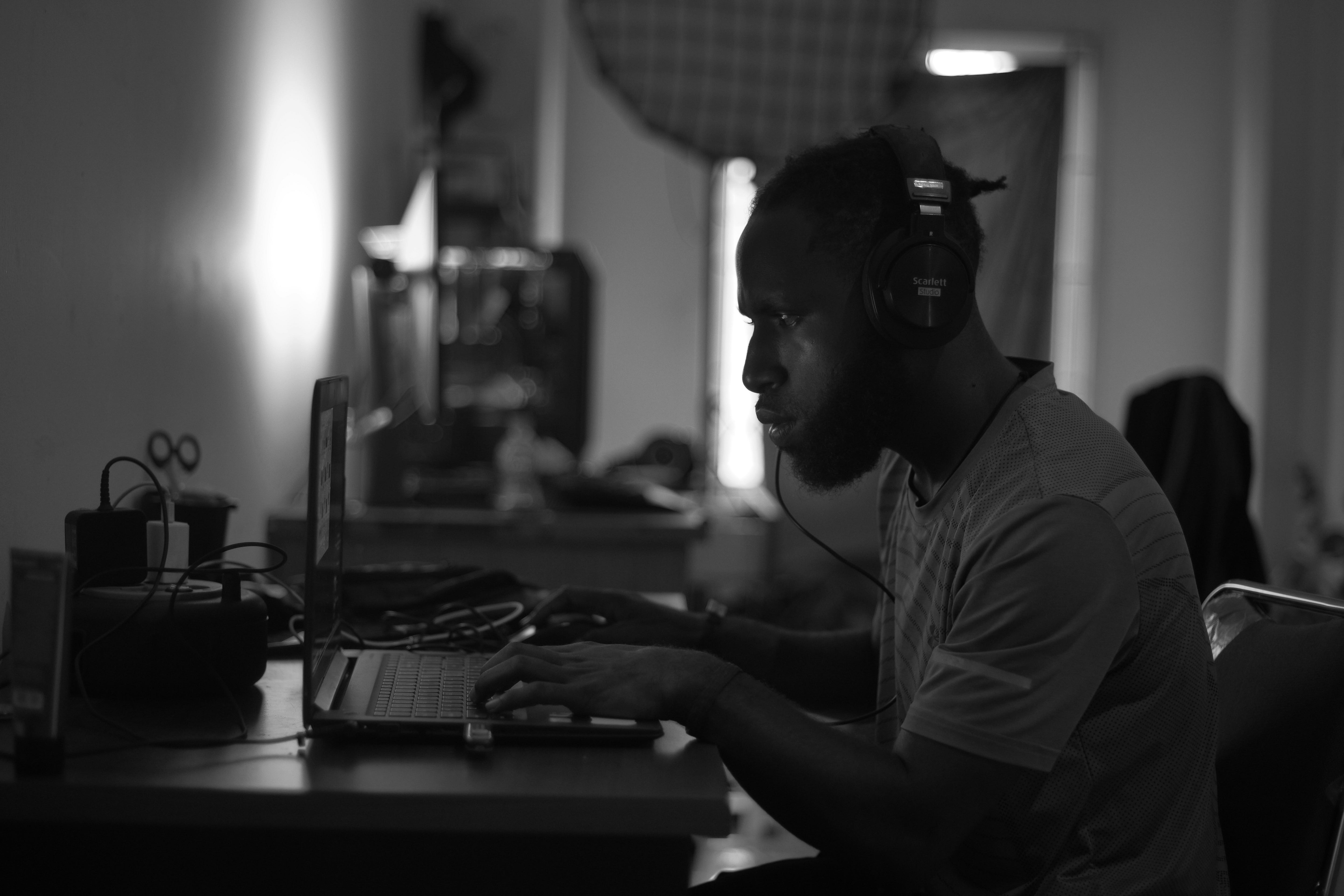 Young Nigerian freelancer working on a laptop at a home office desk, reviewing income and tax documents.