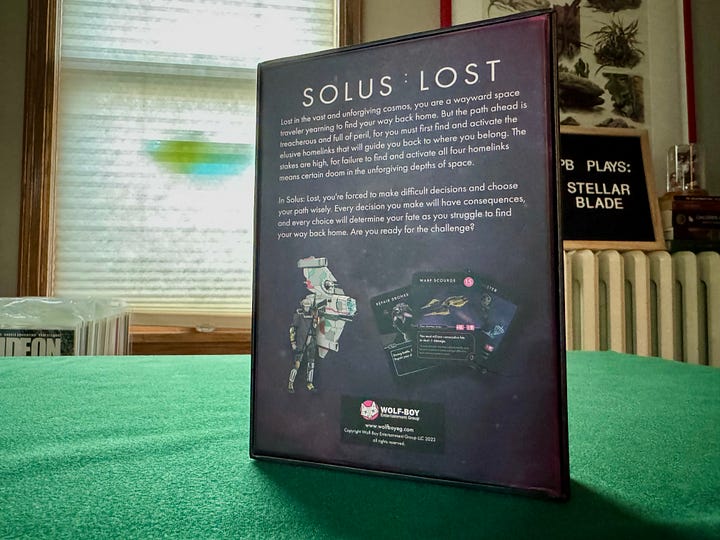 Solus: Lost, a card drawing, sci-fi, boss battler. The box is all black with pink design flourishes.