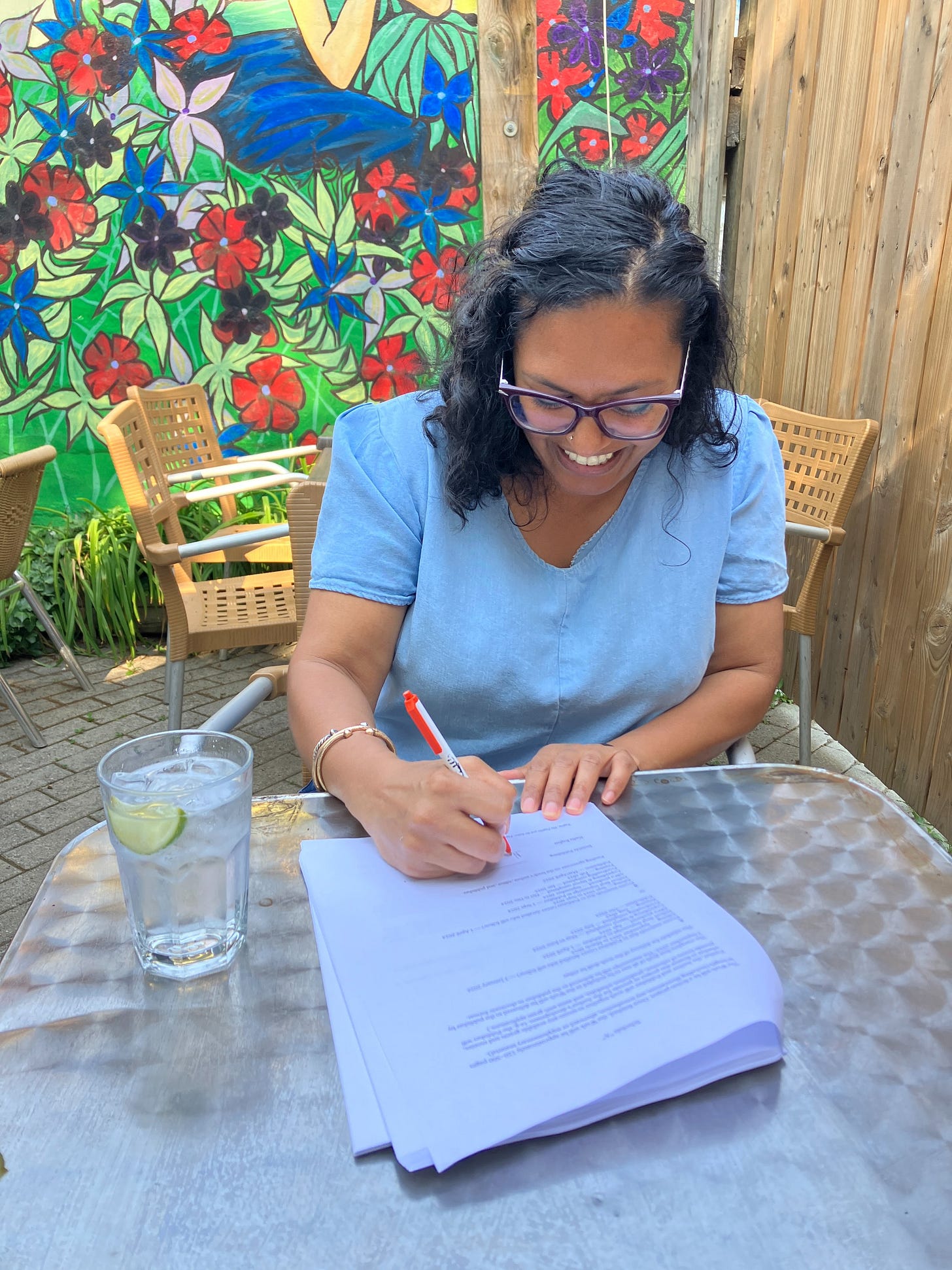 A woman in a blow top signing a contract on a bar patio.