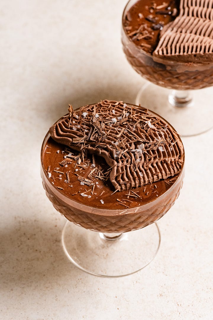 Hazelnut chocolate mousse topped with chocolate whipped cream in glass goblets.