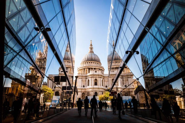 Urban crowd and futuristic architecture in the city, London, UK Color image depicting a crowd of people, thrown into silhouette and therefore unrecognisable, walking alongside modern futuristic architecture of glass and steel. In the distance we can see the ancient and iconic dome of St Paul's cathedral. Room for copy space. uk economic growth stock pictures, royalty-free photos & images