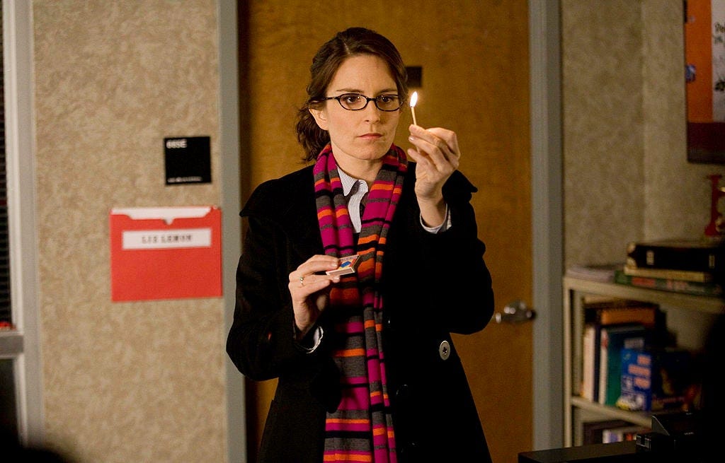 A woman wearing a coat and striped scarf holds a lit match in front of her face.