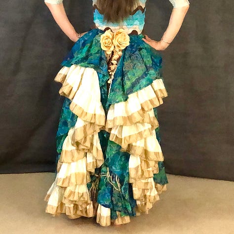 A variety of skirts bustled in the back with flowers and yarn dangles creating a centerpiece between the ruffles.