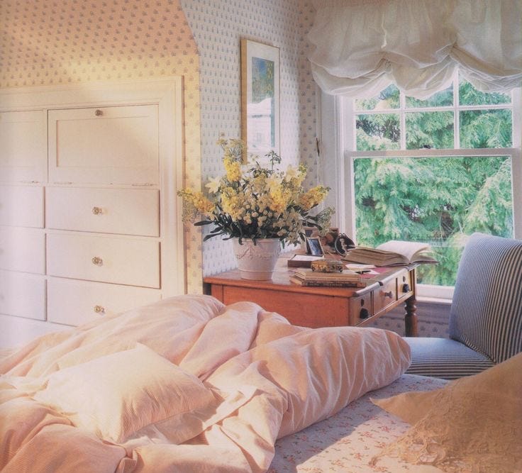 This may contain: a room with a bed, dresser and window that has flowers in the vase on it