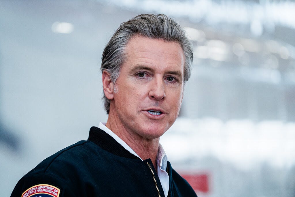 Gov. Gavin Newsom is at a news conference, where he is wearing a California Department of Forestry and Fire Protection jacket.