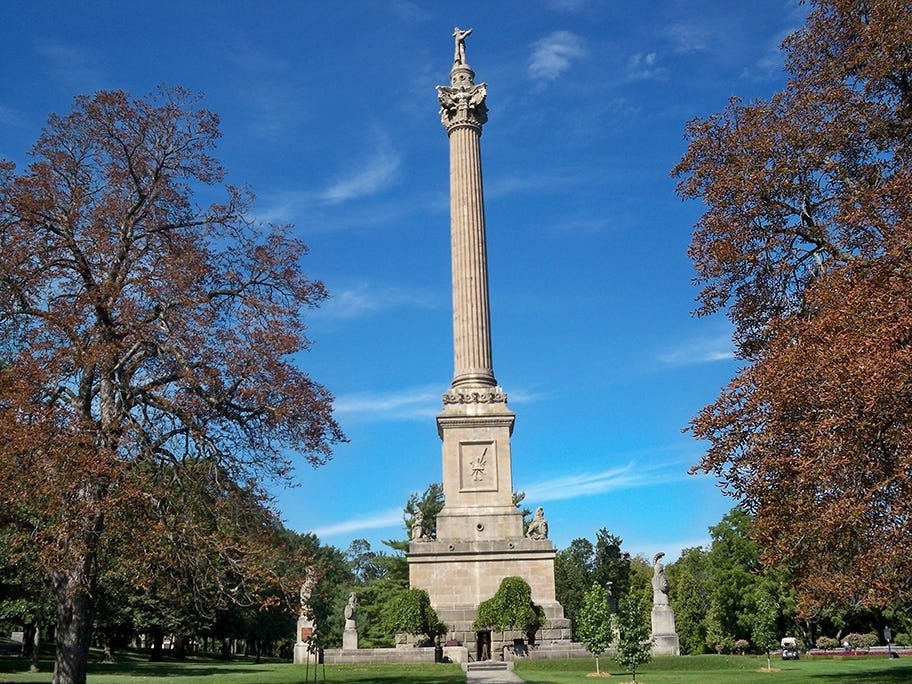 A tall monument with trees and blue sky

Description automatically generated