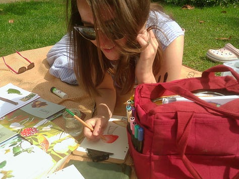 girl on the picnic blanket journaling with art supplies
