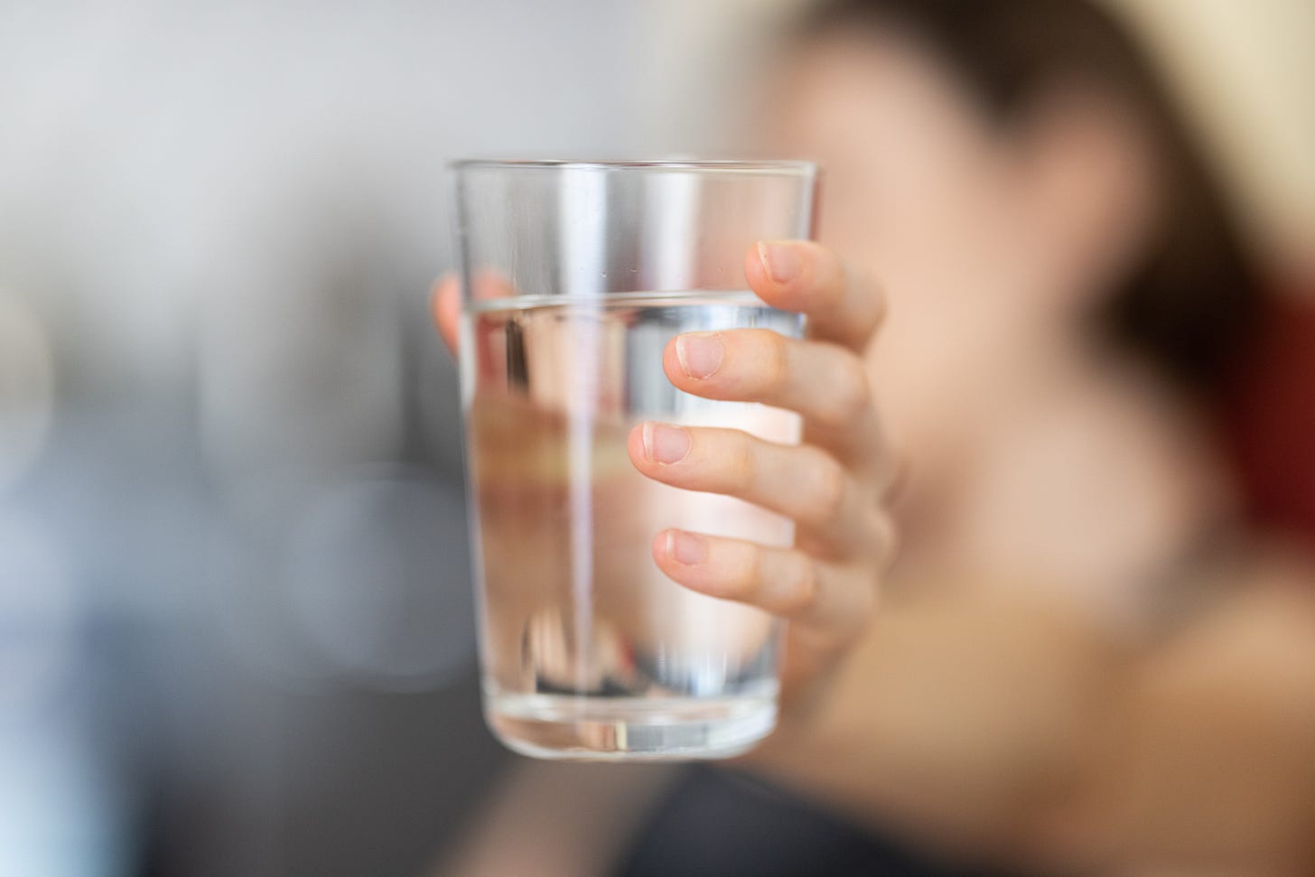 A pale hand holding a delicious snack consisting of a glass of plain water A pale hand holding a delicious snack consisting of a glass of plain water