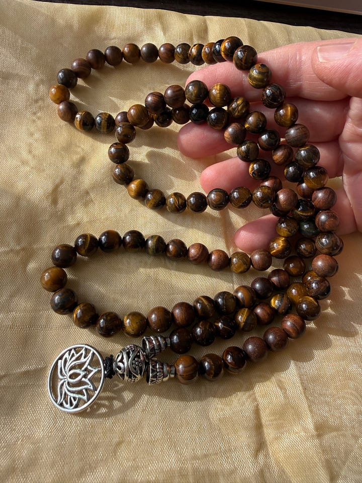 A variety of bead bracelets in various colors and pink mala beads and tiger's eye mala beads