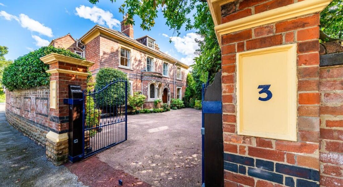An exterior of a brick house next to a brick wall with a gate and a number three painted to the right An exterior of a brick house next to a brick wall with a gate and a number three painted to the right