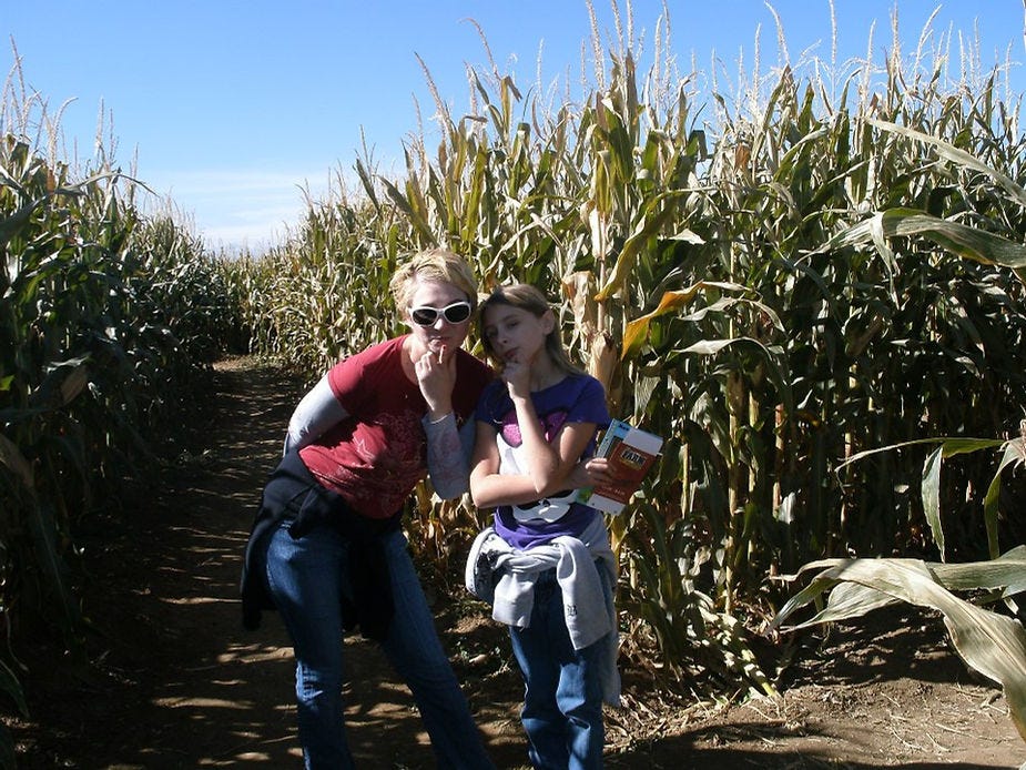 Mom and daughter holding a map and standing in front of corn maze enterance.