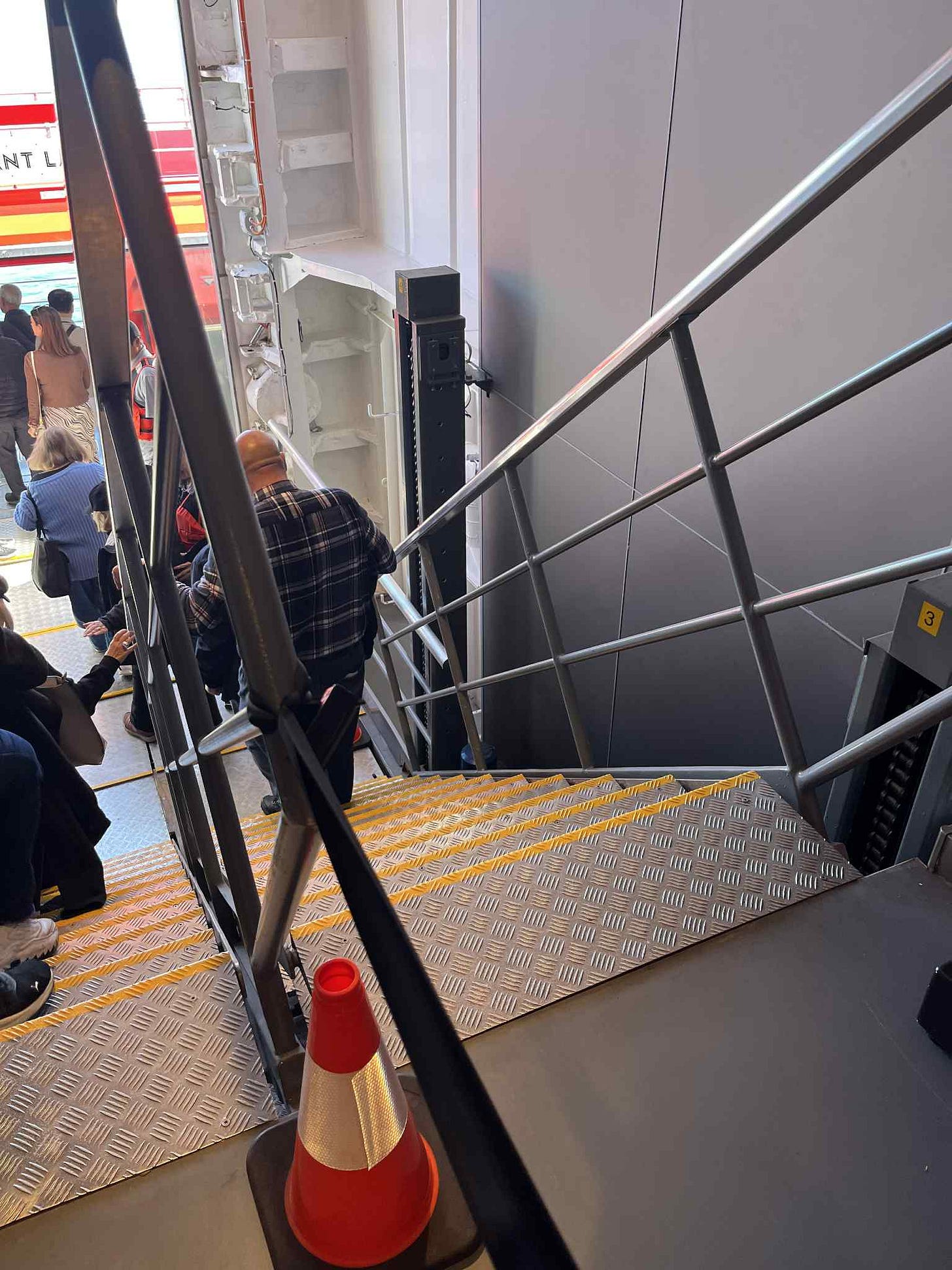 Steep metal staircase with about ten steps leading down to one of Brilliant Lady's lifeboats, which was used as a tender. In the photo, some people are walking down the staircase while others are waiting in line at the bottom of the staircase to board the small vessel.